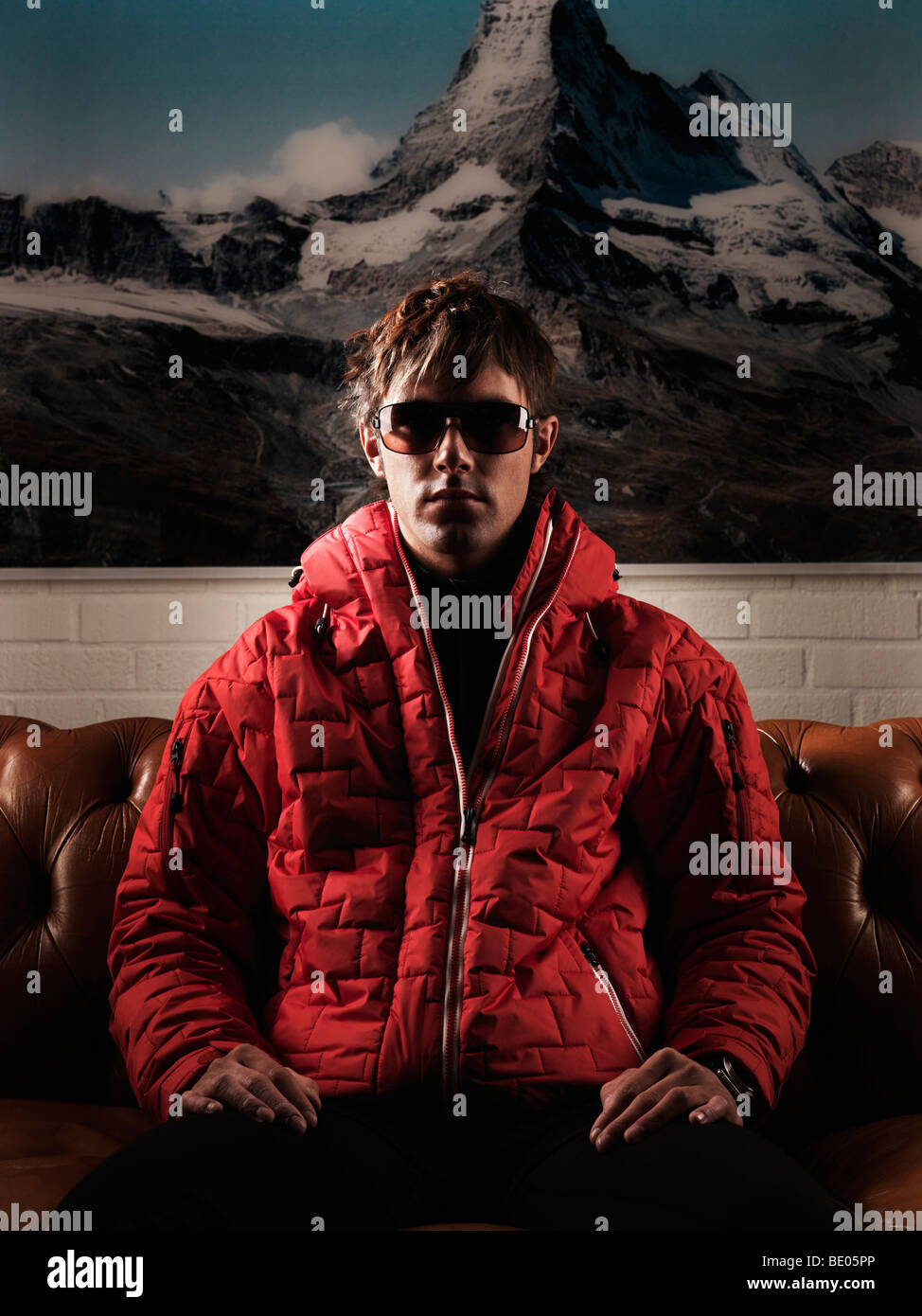 Man in red jacket sitting on couch Stock Photo Alamy