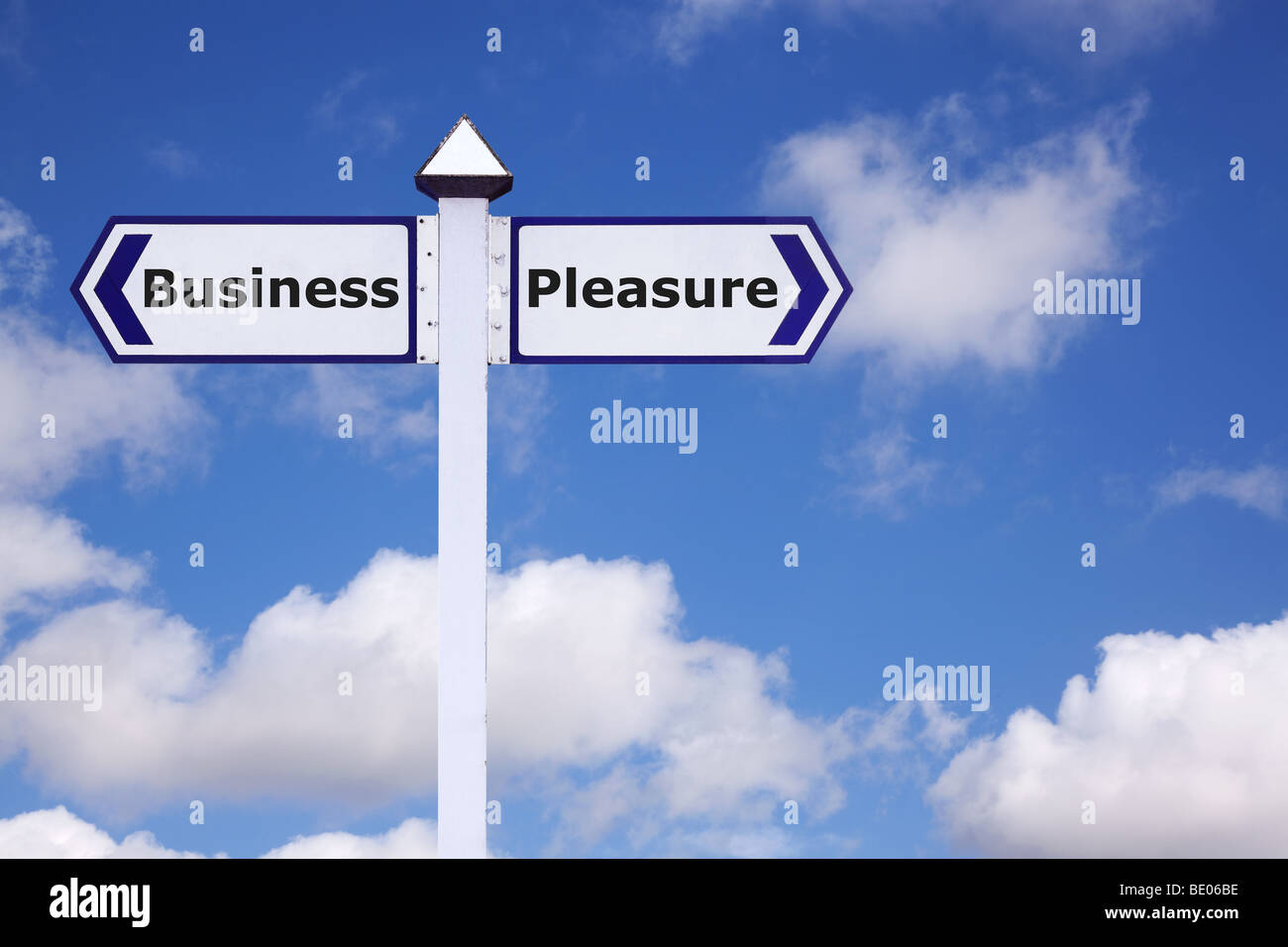 Business and Pleasure on a signpost against a blue cloudy sky Stock Photo