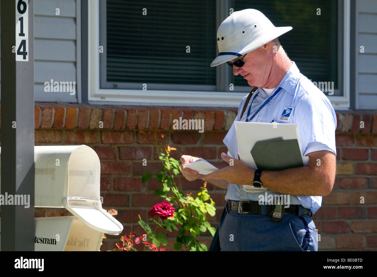 Postman delivering mail to a residence in Boise, Idaho, USA. Stock Photo