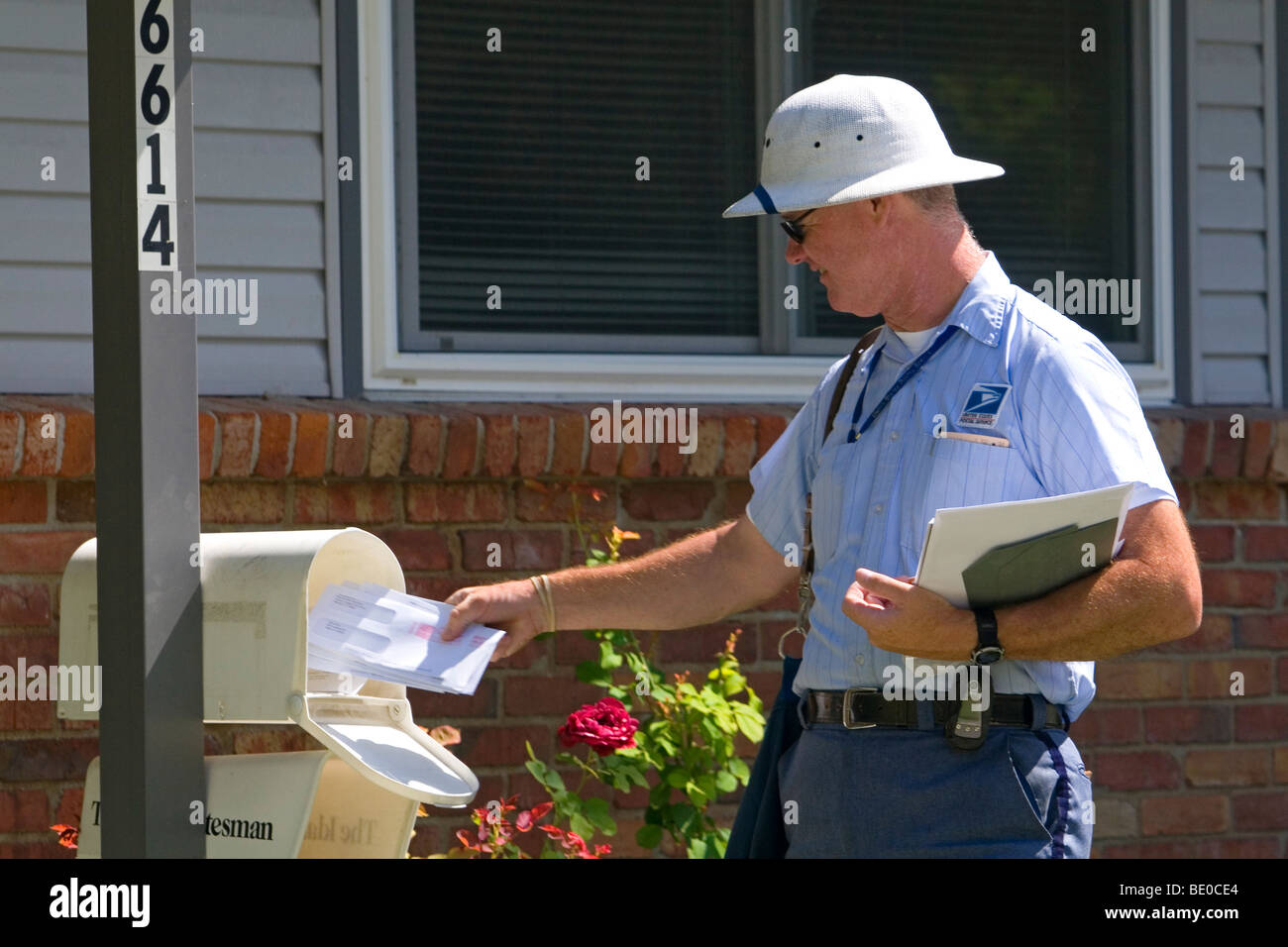 Postman delivering mail to a residence in Boise, Idaho, USA. Stock Photo