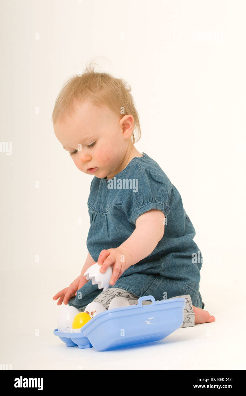 Baby girl playing with toy eggs and eggbox in a studio Stock Photo