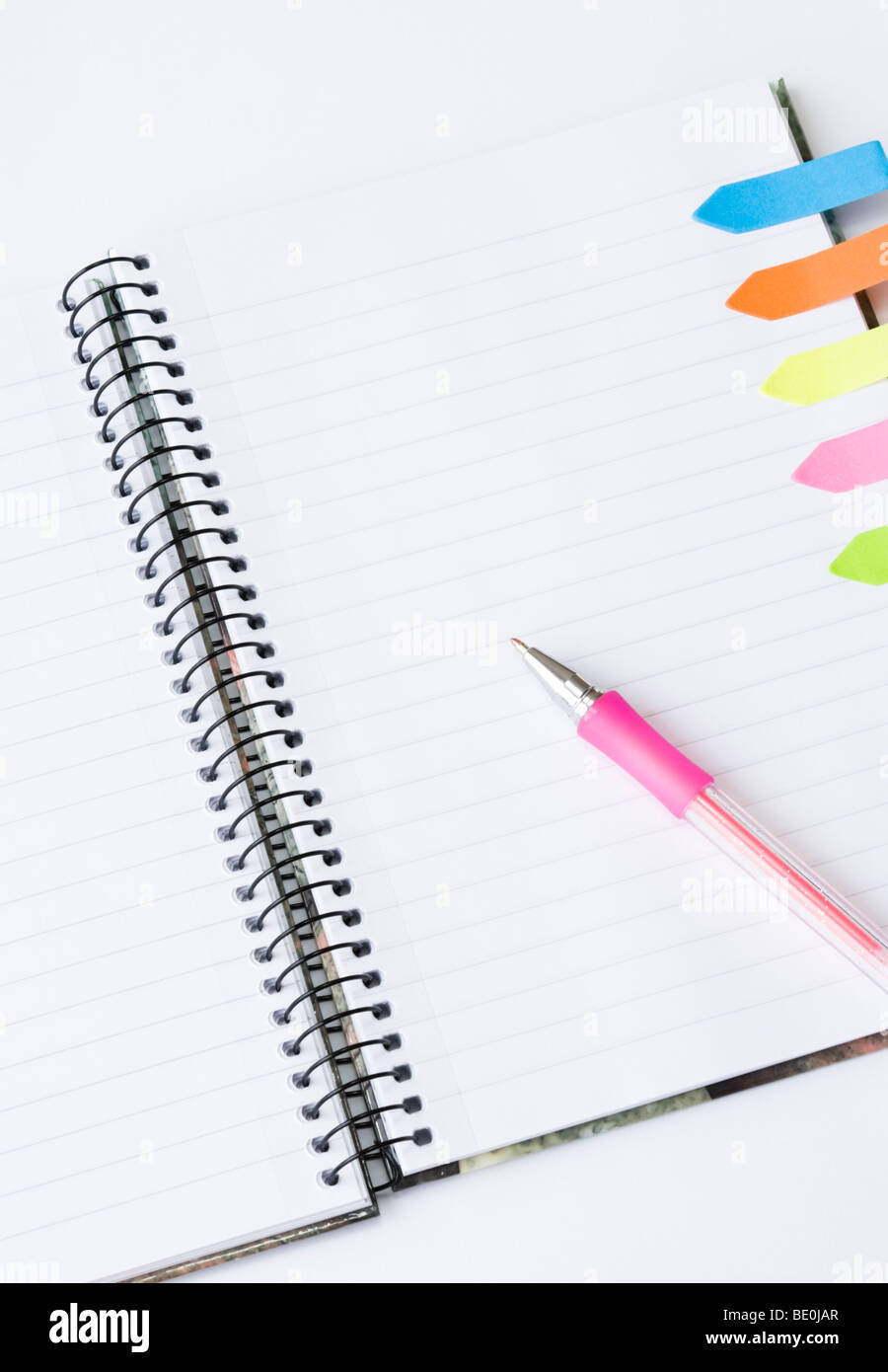 Lined spiral notepad with colorful postit sticky notes and pink pen isolated on white background Stock Photo