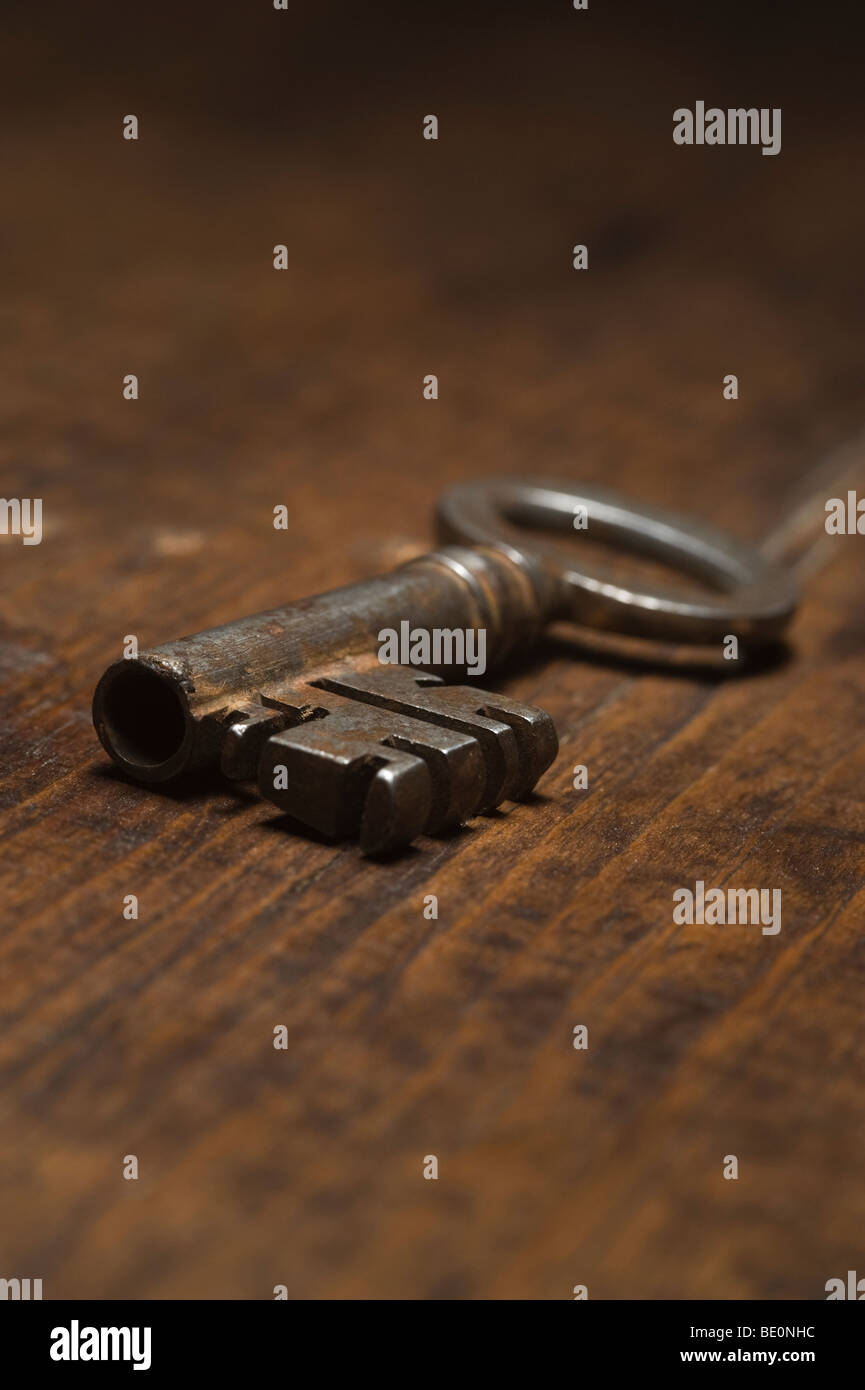 Low angle view of antique key on a wooden surface. Stock Photo