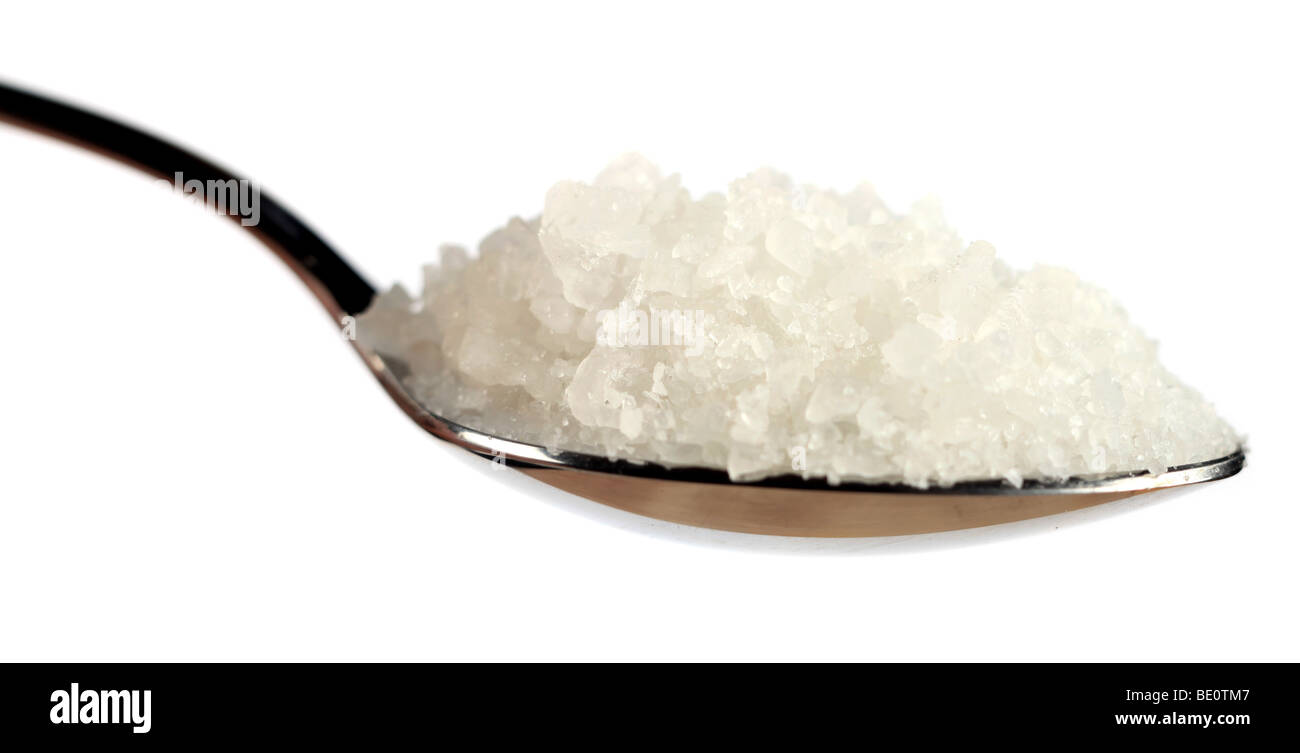 A spoon of coarse sea salt against a white background, extreme close-up Stock Photo