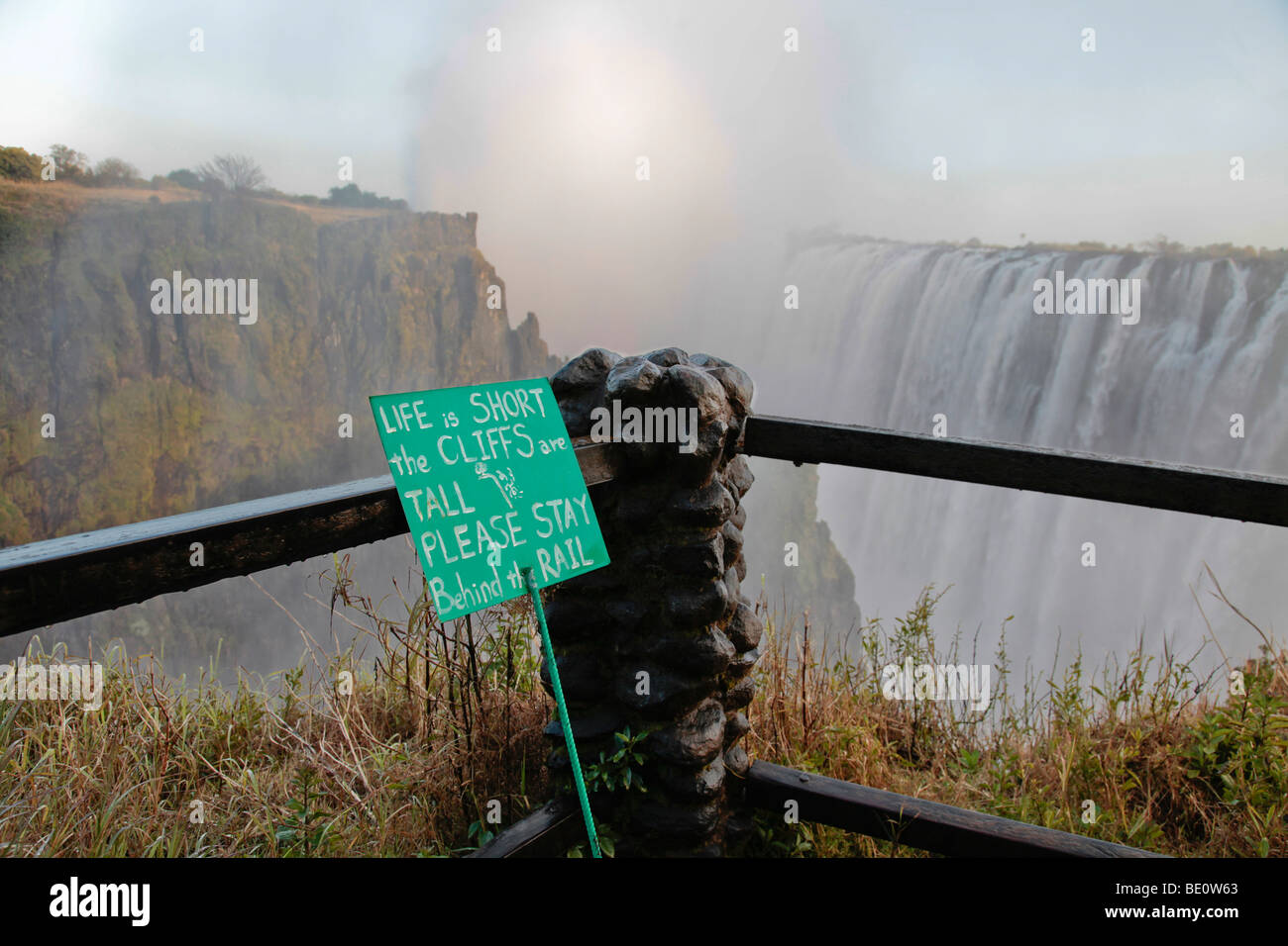 Warning notice at the edge of a cliff at Victoria Falls, Zambia. 'Life is short, the cliffs are tall' Stock Photo