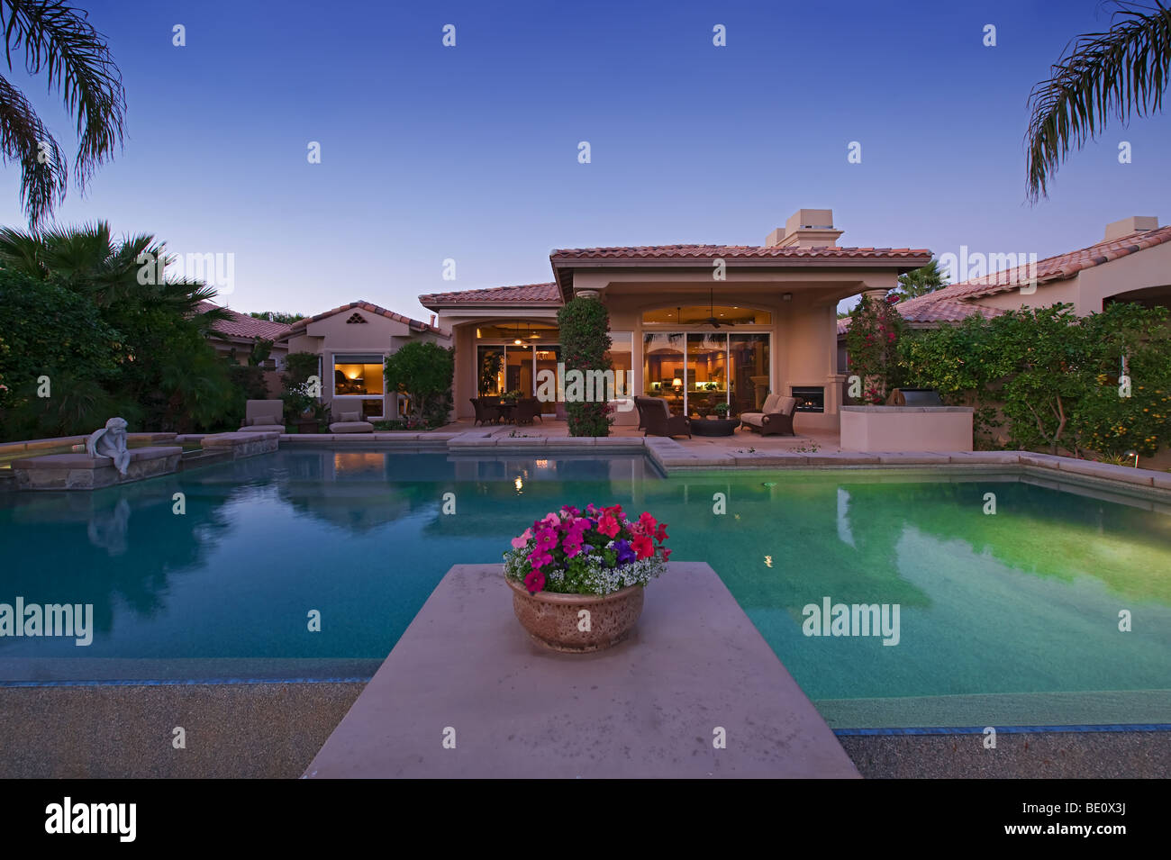 View across swimming pool at luxury home at dusk Stock Photo