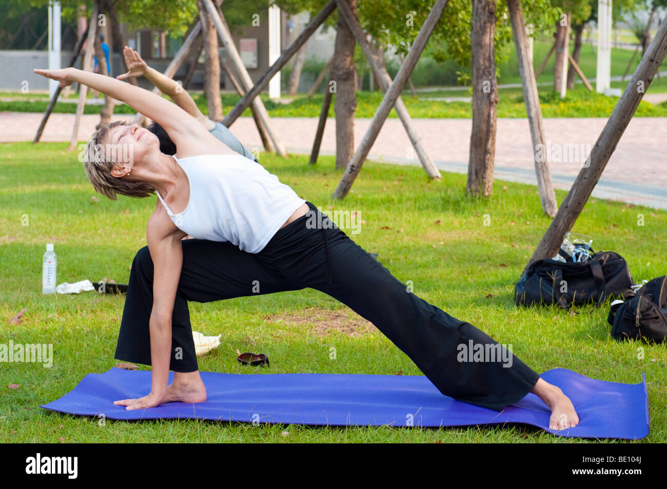 Woman Stretching Doing Yoga Outdoors In Park Stock Photo