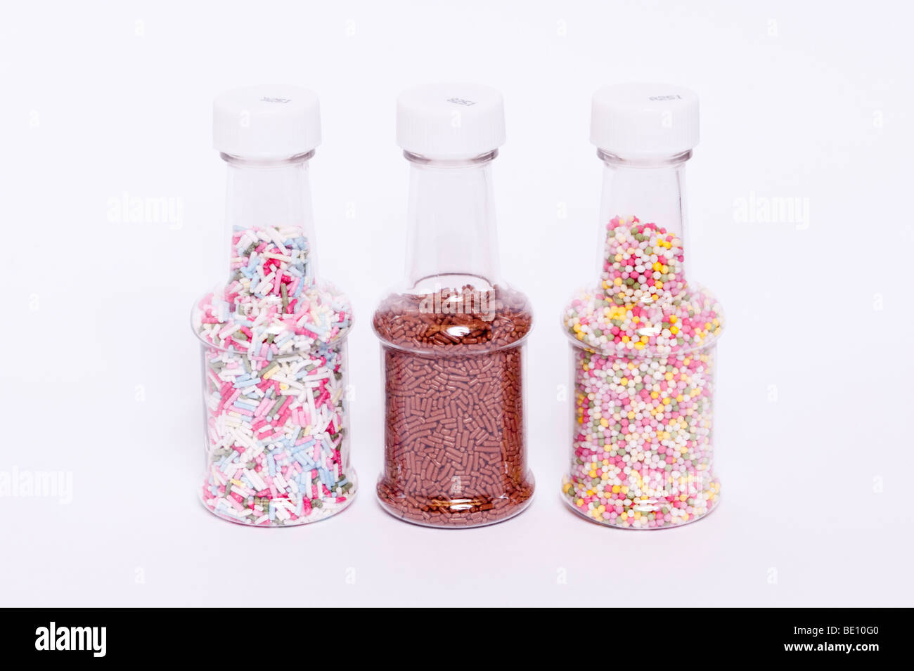 A close up of 3 jars of coloured hundreds and thousands cake decorations on a white background Stock Photo
