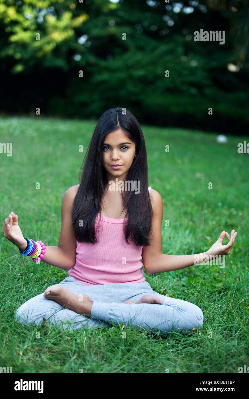 YOUNG TEENAGER GIRL DOING YOGA EXERCISES IN THE GARDEN Stock Photo