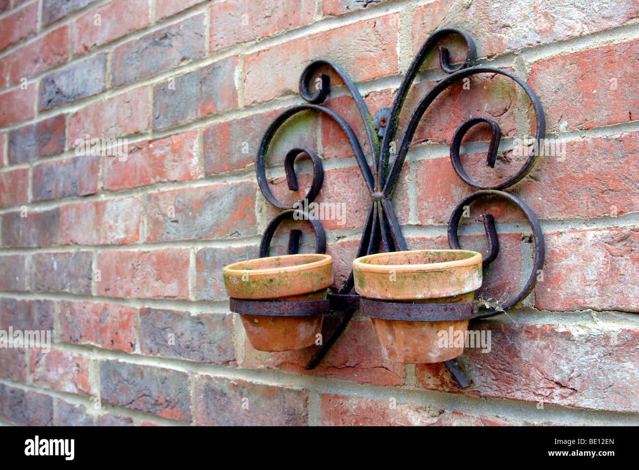 Empty terracotta pots hanging on wall in metal bracket Stock Photo