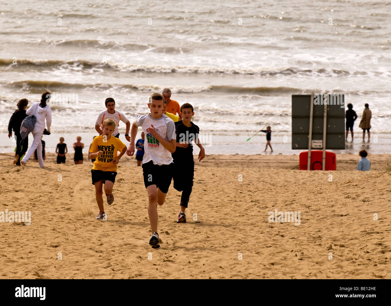Young athletes running up a sand dune on the beach at Camber Sands in East Sussex.  Photo by Gordon Scammell Stock Photo