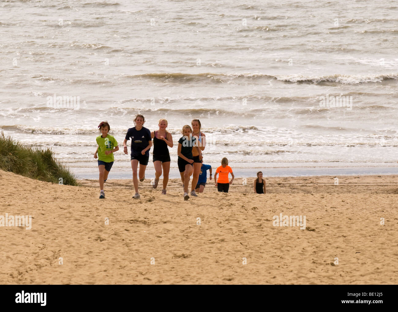 Young athletes running up sand dunes on the beach at Camber Sands in East Sussex.  Photo by Gordon Scammell Stock Photo