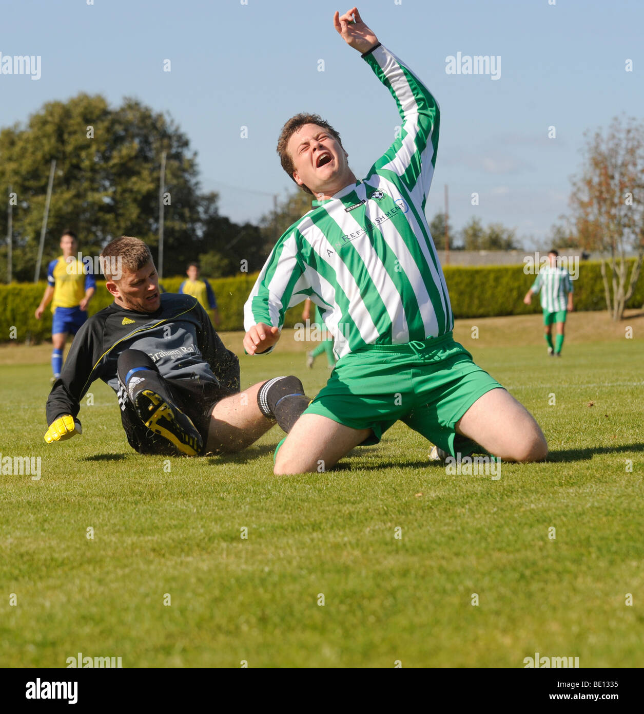 Tow football players clash in a tackle at a local level football match in Rotherfield, East Sussex. UK Stock Photo