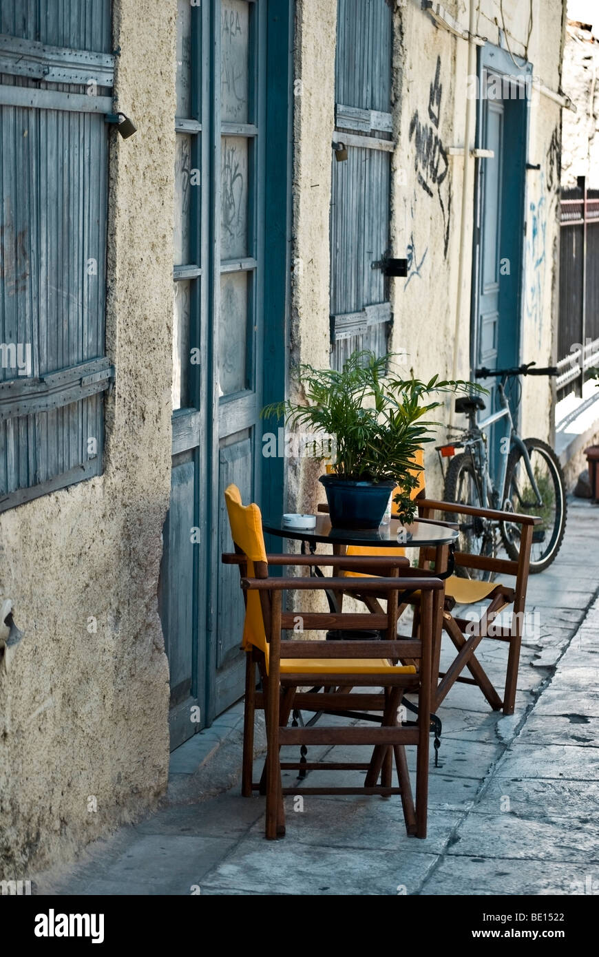 A set of table and chairs on the street outside a house with blue shutters. Stock Photo