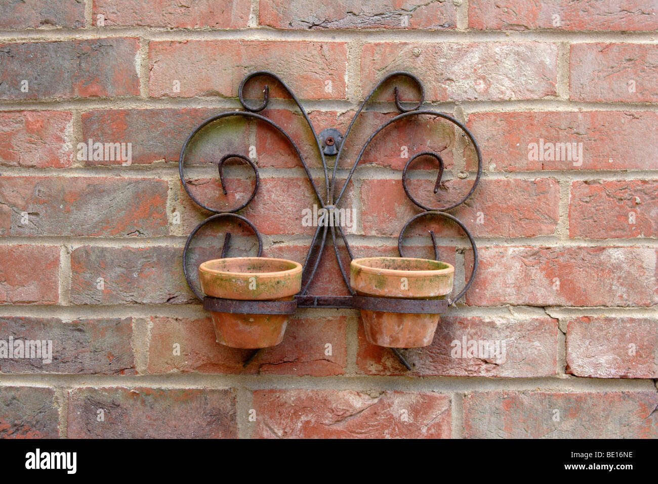 Empty terracotta pots hanging on wall in metal bracket Stock Photo