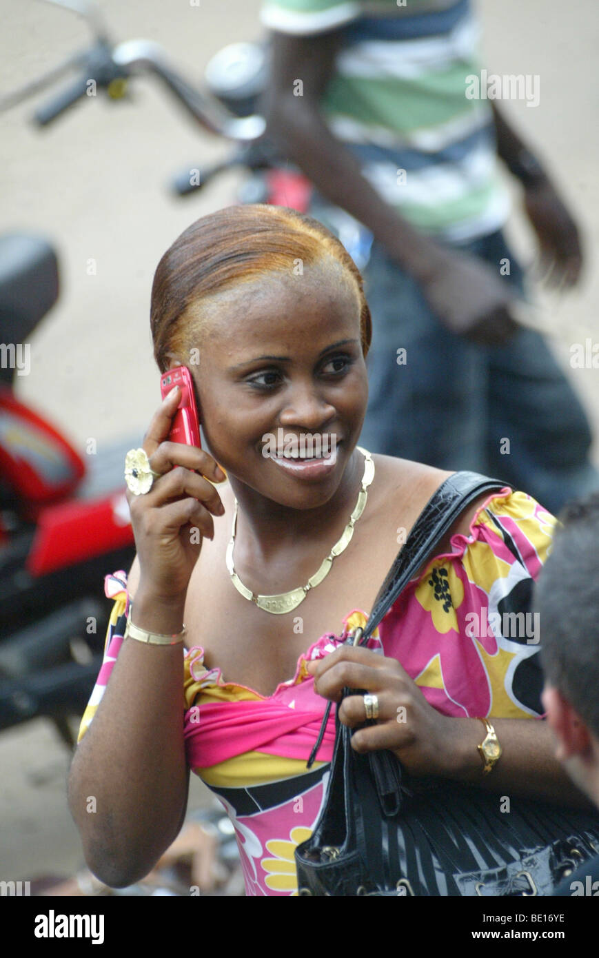 Monrovia, Liberia - September , 6, 2008: A lady responding to a phone call as she walks through a major street(Broad St.) down Stock Photo