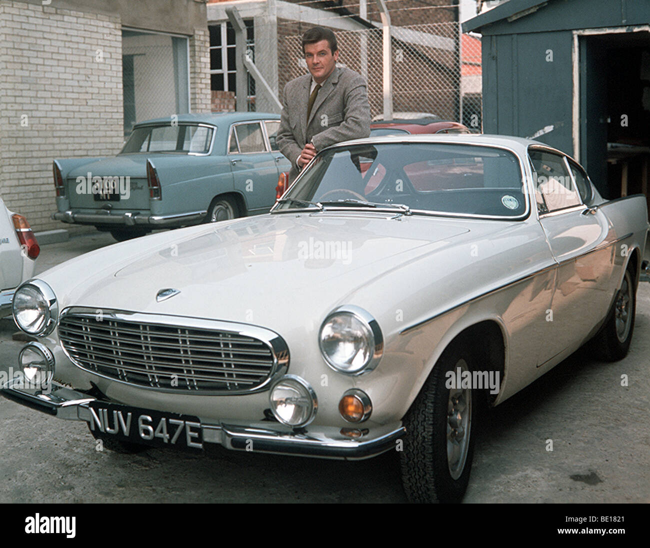 THE SAINT - UK TV series with Roger Moore seen here on the Elstree Studios back lot with the white Volvo P1800 used in the show Stock Photo
