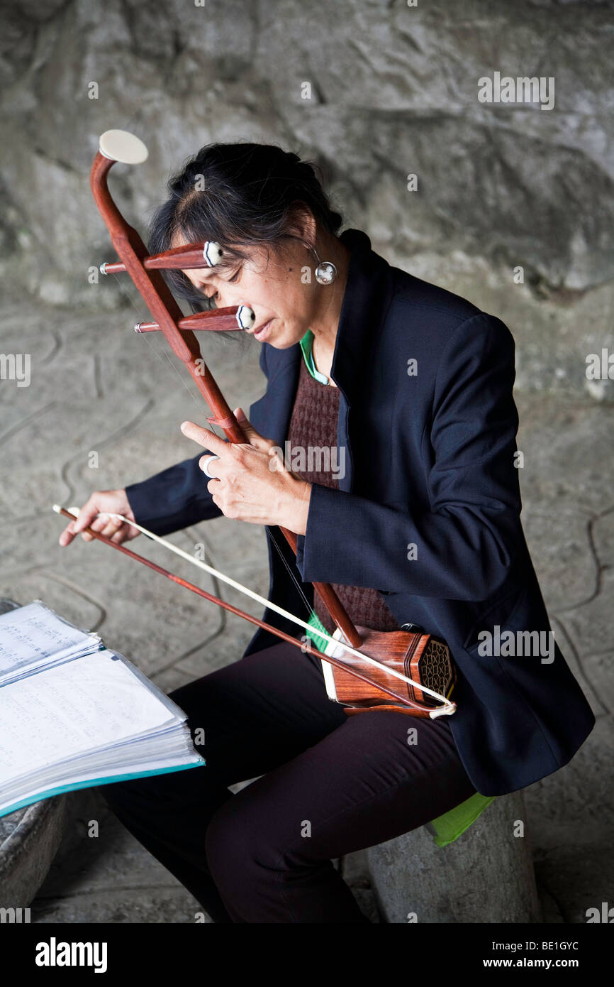 woman in Guangsho playing the traditional bow instrument Erhu, the chinese violin Stock Photo