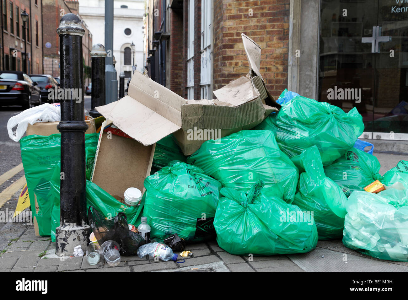 rubbish in bags on a street corner along hanbury street london uk Stock Photo