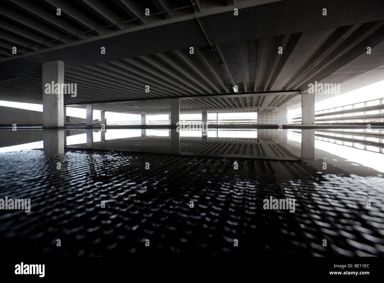 Inside an empty multi storey car park with a puddle covering the floor. Stock Photo