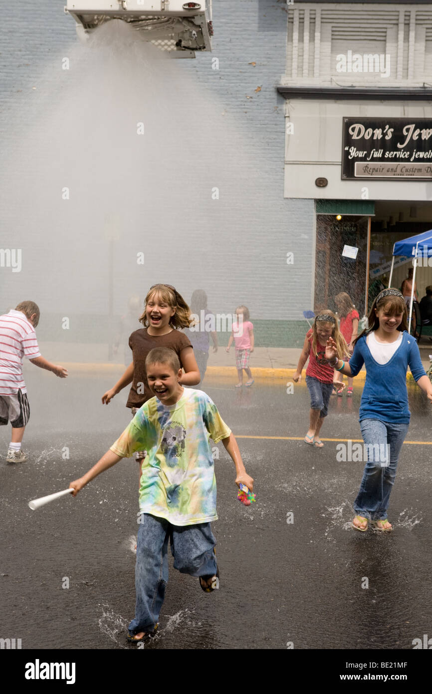 Kids running though sprinkler at a street fair in La Grande Oregon Stock Photo
