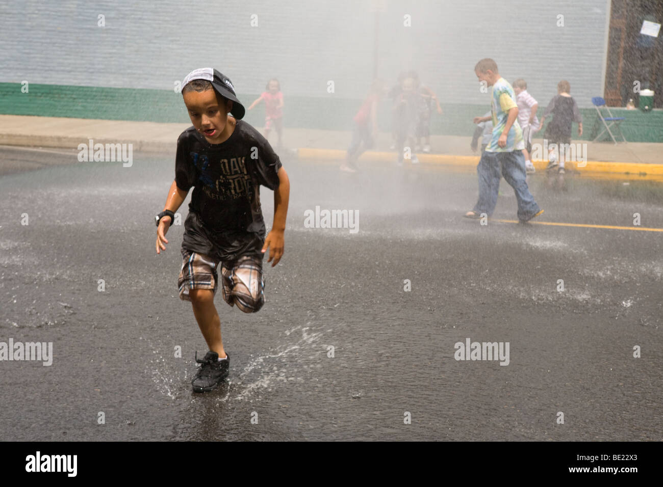 Kids running though sprinkler at a street fair in La Grande Oregon Stock Photo