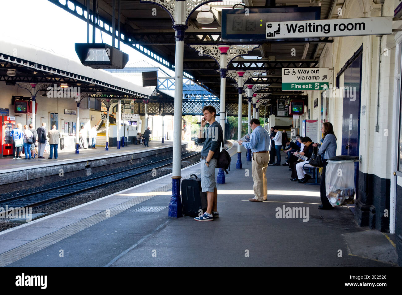 People waiting for a train on a, typically English, railway station platform. (Cheltenham, Gloucestershire ) Stock Photo