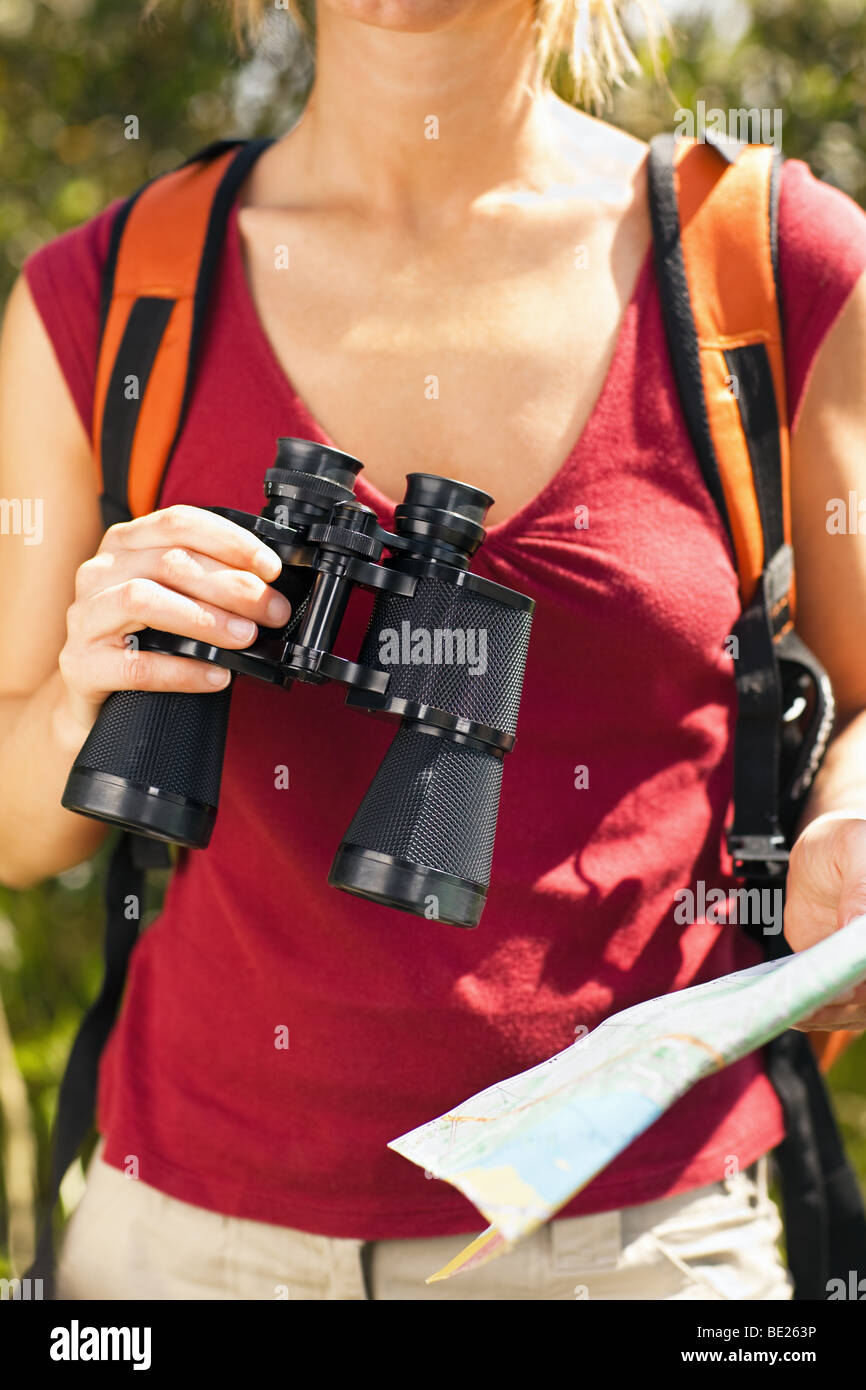 cropped view of female bird watcher holding binoculars and map. Stock Photo