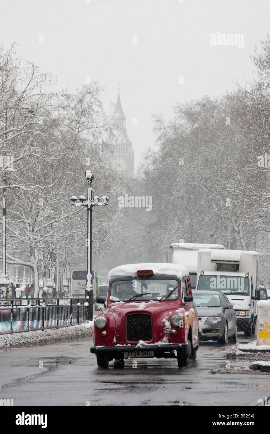 London taxi on Victoria Embankment with Big Ben behind during heavy snow Stock Photo