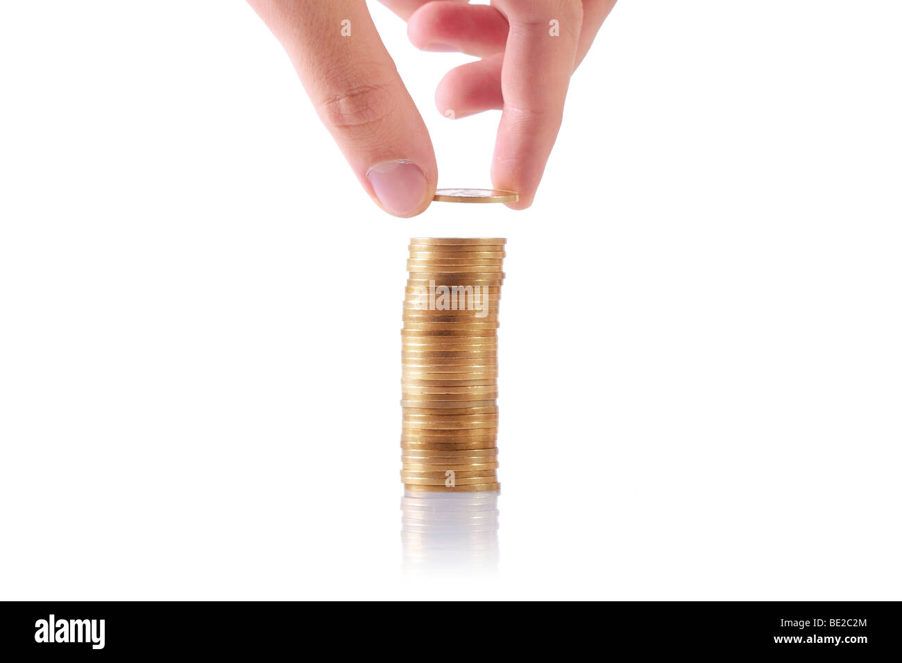hand adding a coin to a stack of coins Stock Photo