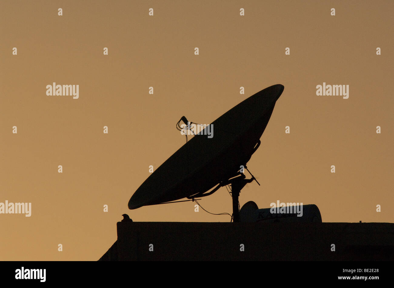 Satellite receiver dish in silhouette against an evening sky. Stock Photo