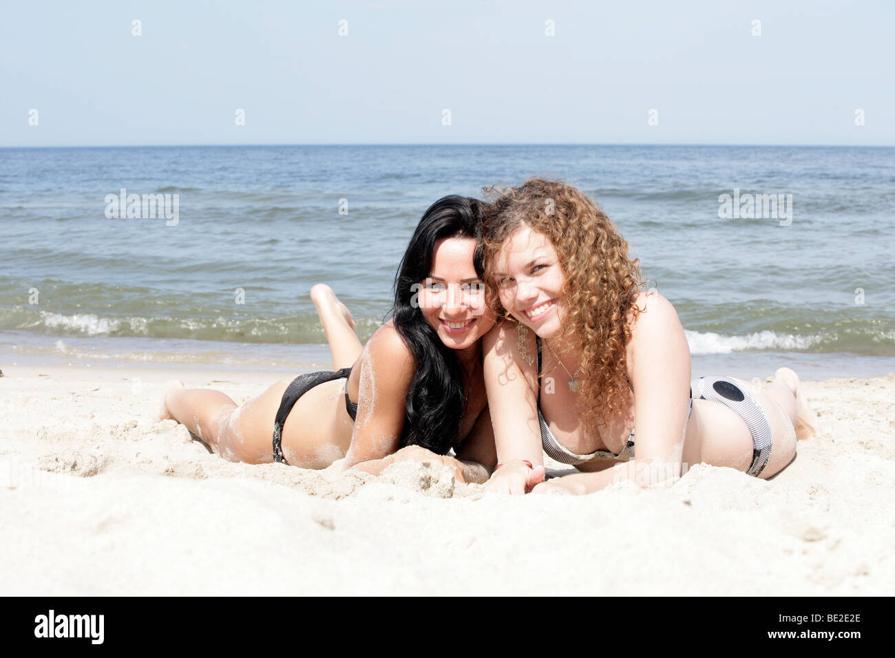 Two alluring women are relaxing on the nudist beach