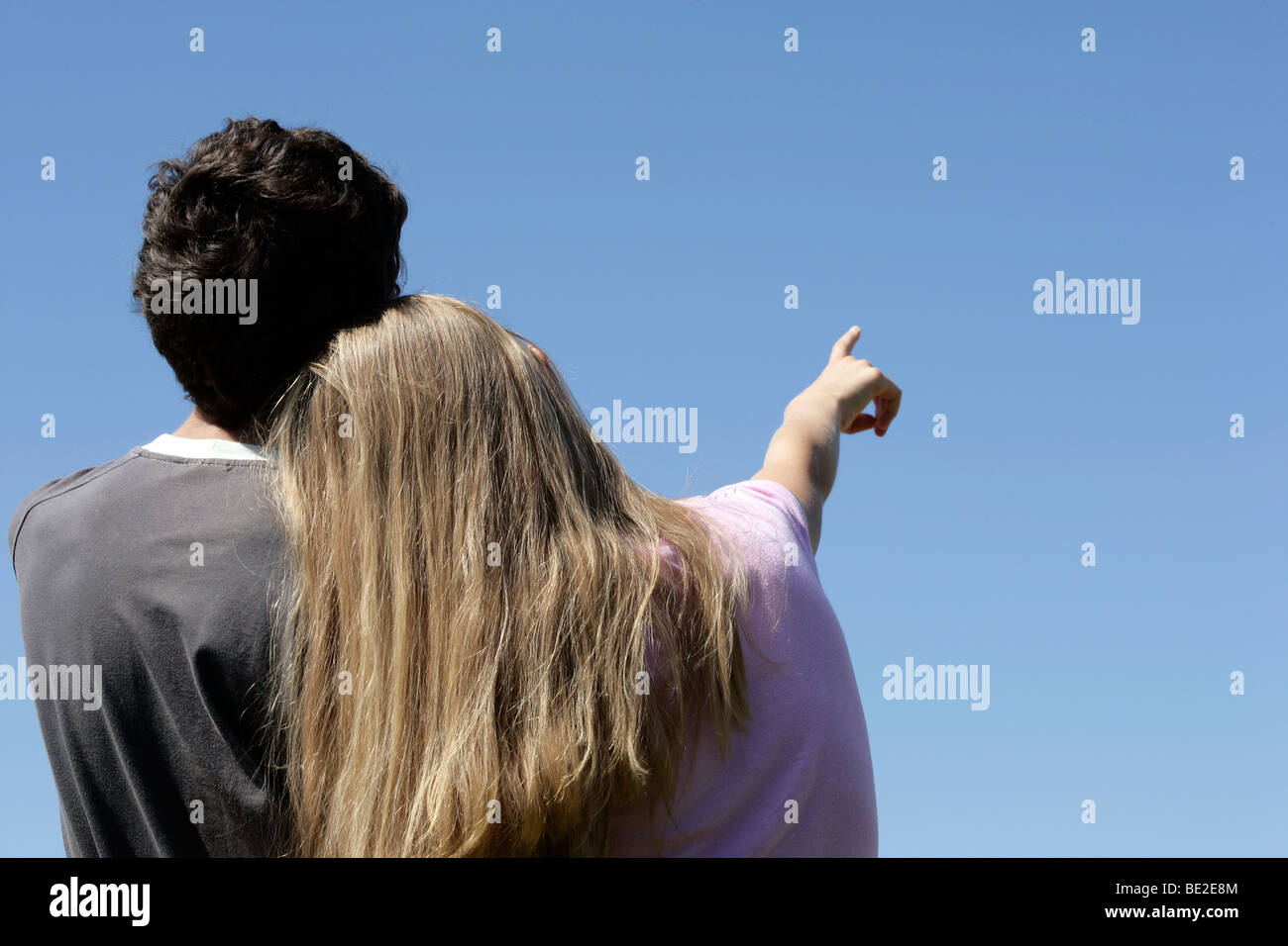 Romantic teenage couple looking at blue sky. Girlfriend pointing Stock Photo