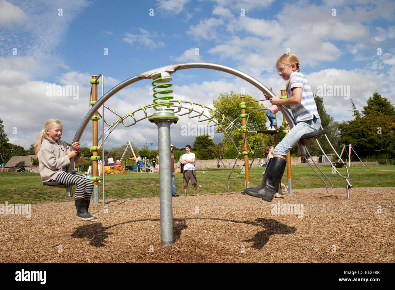Two girls enjoying hitech seesaw at new exciting playground Broadway Activity Park Worcestershire UK Stock Photo