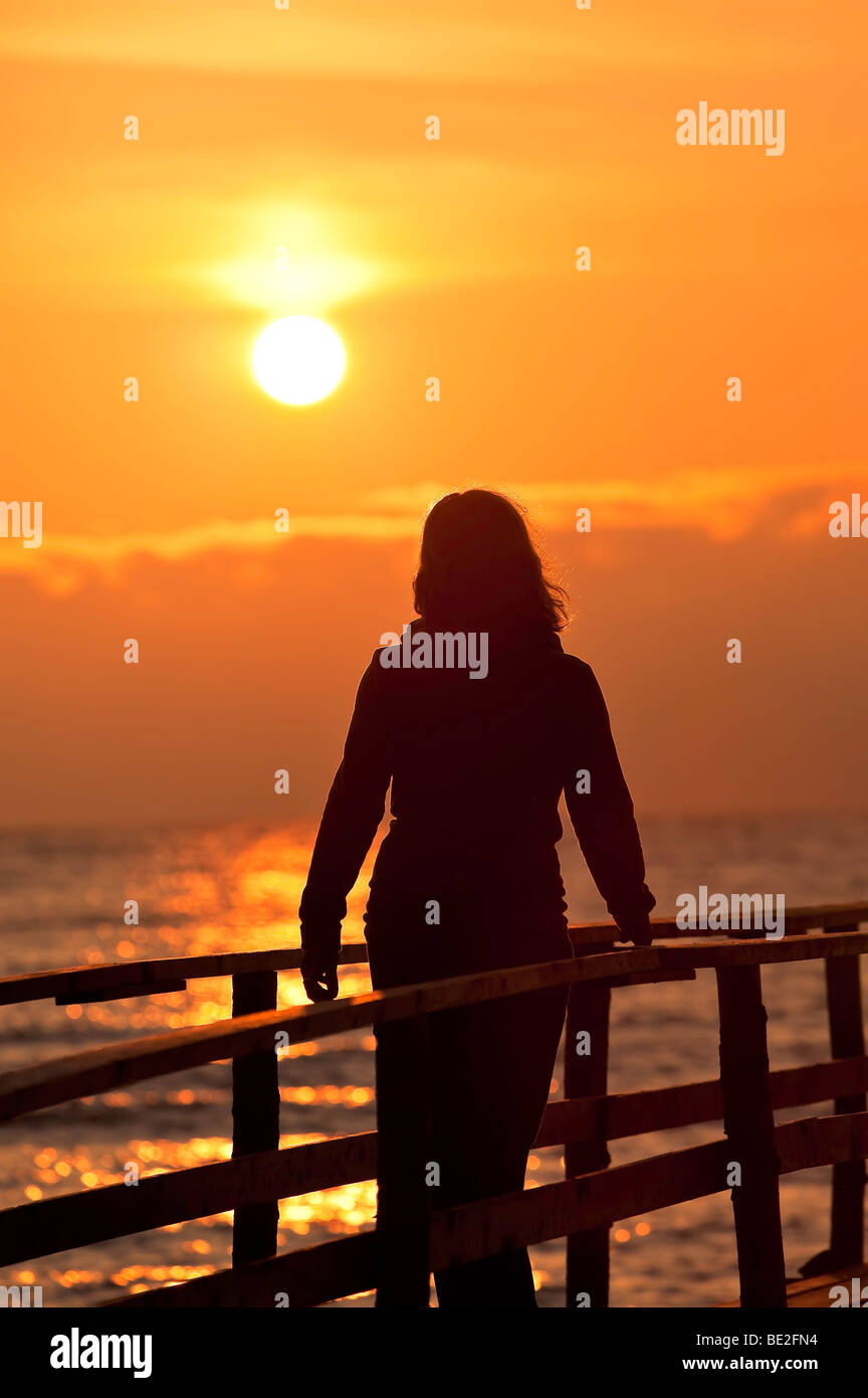 Woman watching sunrise over Lake Winnipeg from a wooden pier, Matlock, Manitoba, Canada. Stock Photo