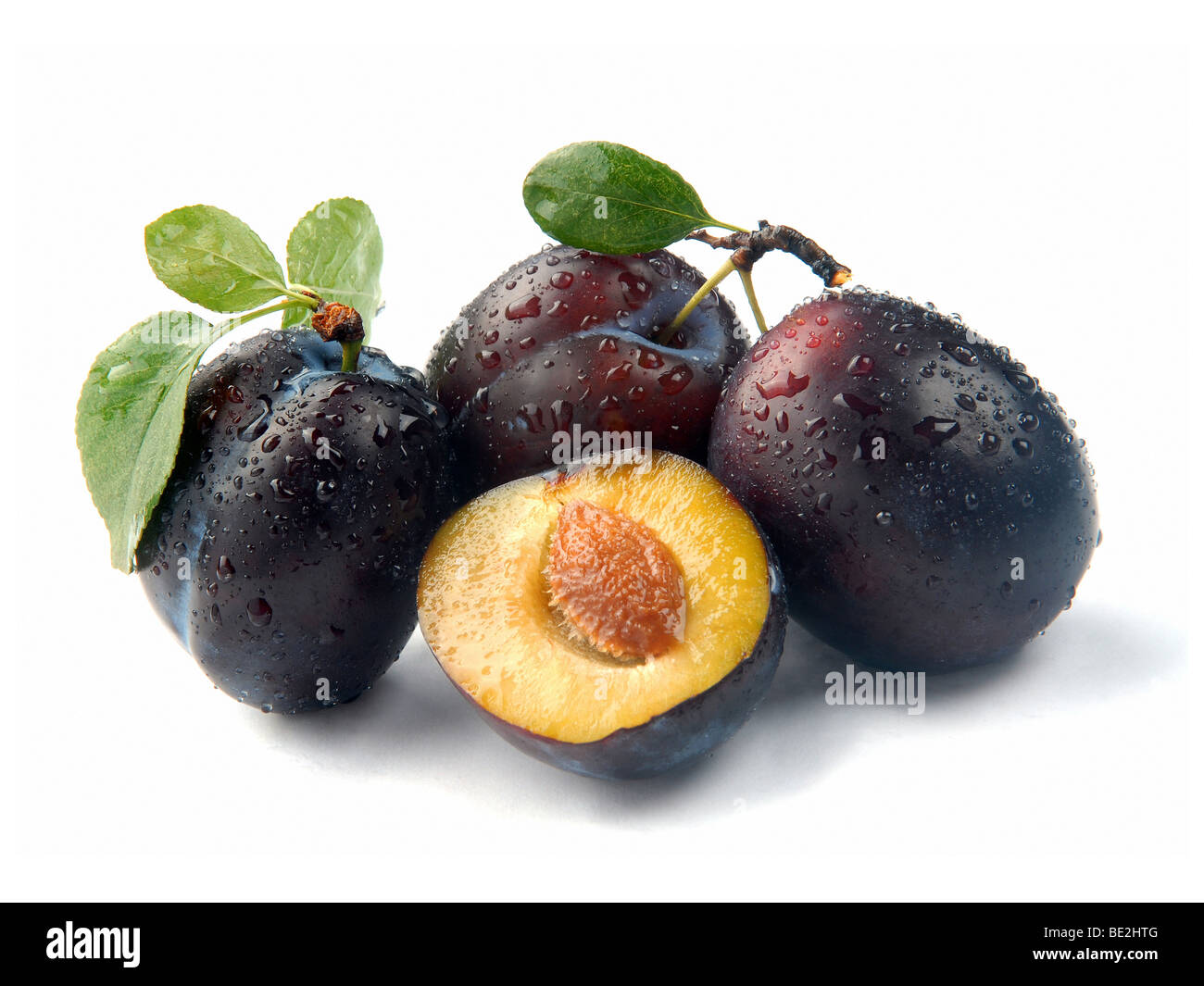 plum and a half and leaves on a white background Stock Photo