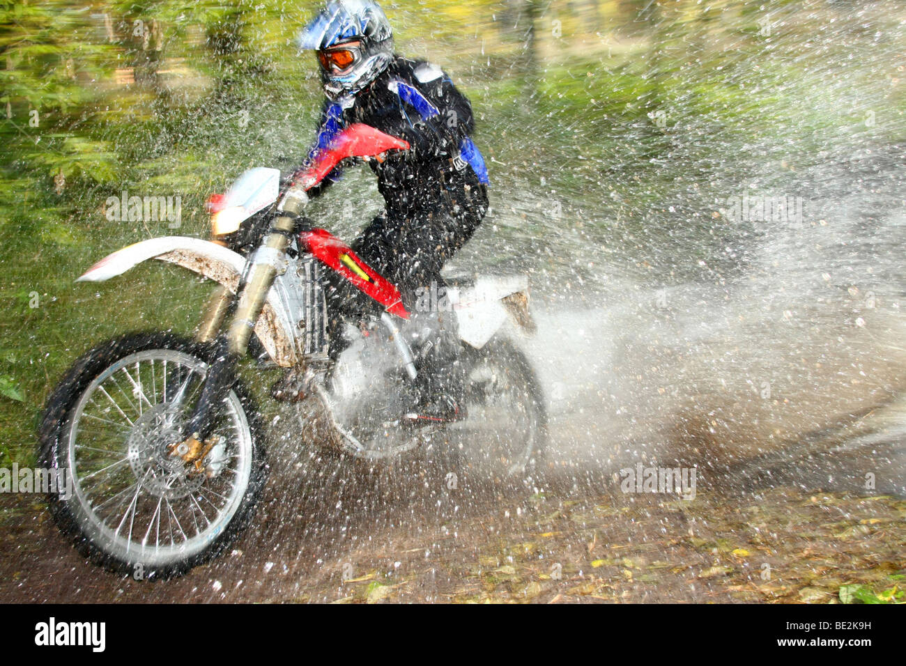 Offroad motorbike crossing river, water splashing around. Dynamic