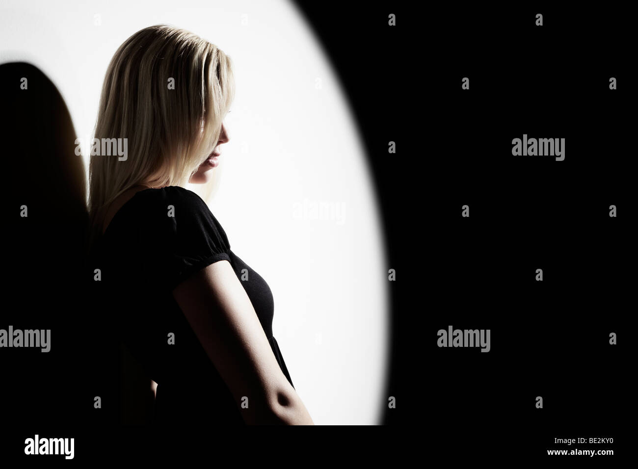 Portrait of a young woman wearing a black dress leaning against a wall Stock Photo