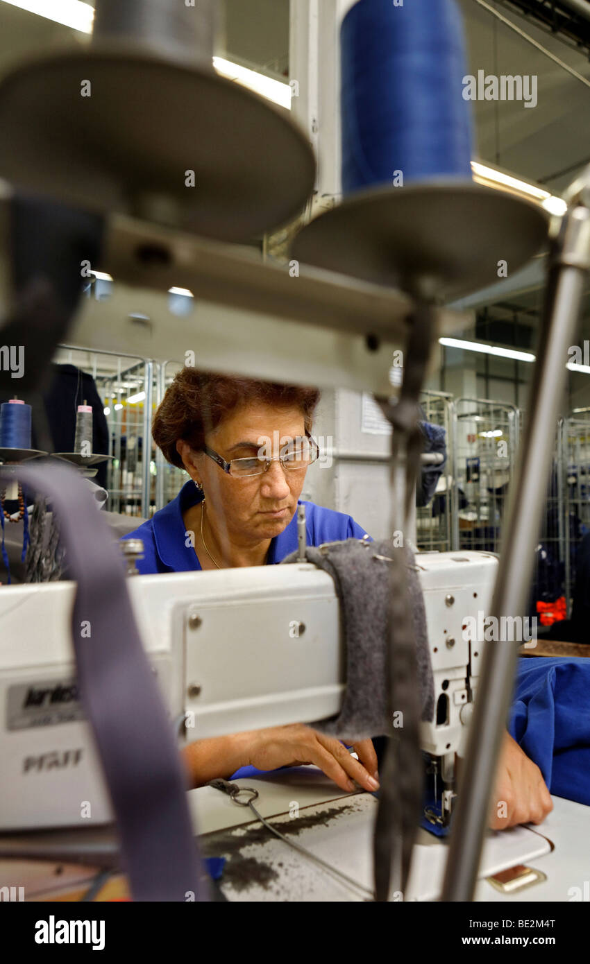 Leyla Civi, employed for 36 years at Bardusch, sewing slightly damaged rental work clothing in the blue section of an industria Stock Photo