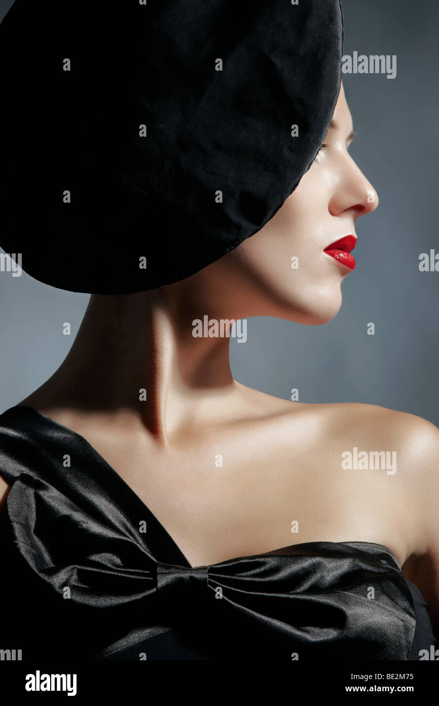 Side portrait of a young woman wearing a black dress and a black hat, fashion Stock Photo