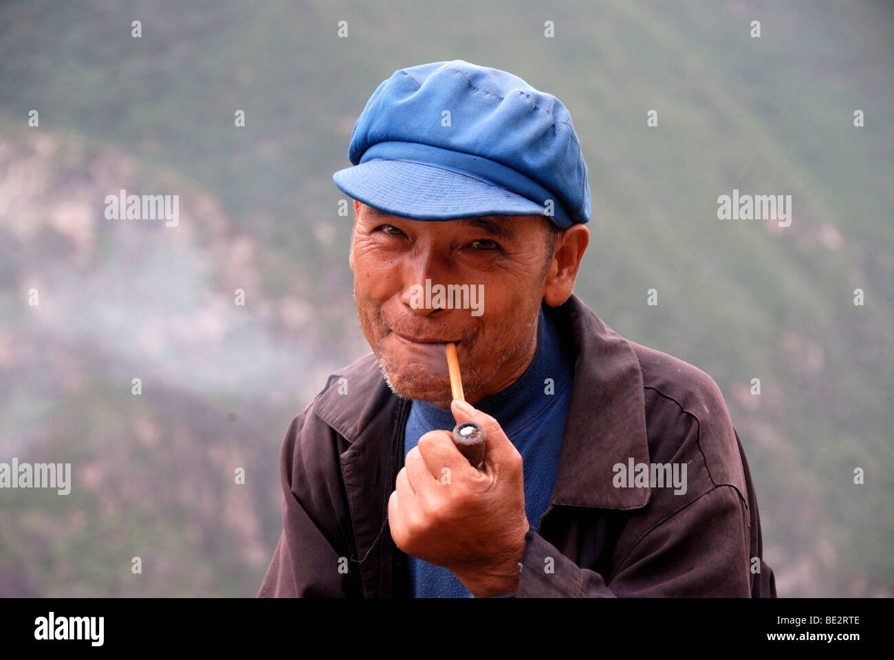 Portrait, ethnology, man of the Naxi ethnic group with a cap, smoking pipe, native, Tiger Leaping Gorge, high trail, Yunnan Pro Stock Photo