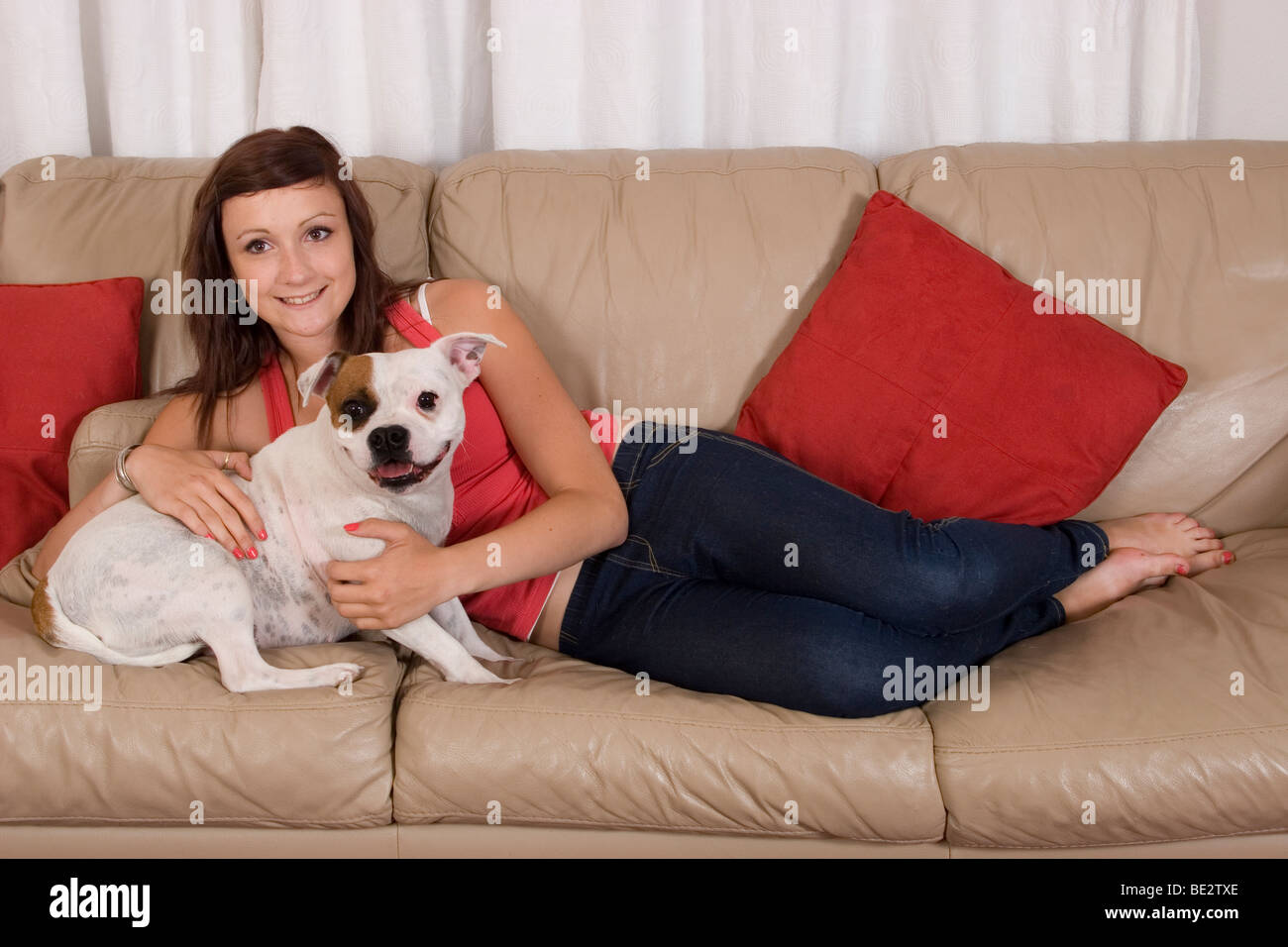 teenage girl on sofa with white staffordshire bull terrier adult dog Stock Photo