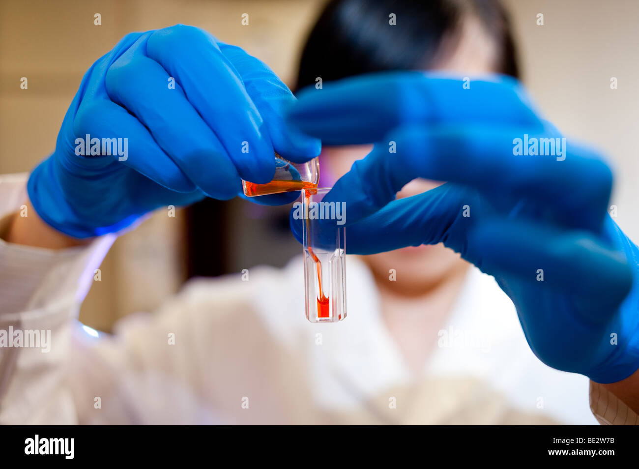 A female science student transfers solution into a beaker Stock Photo