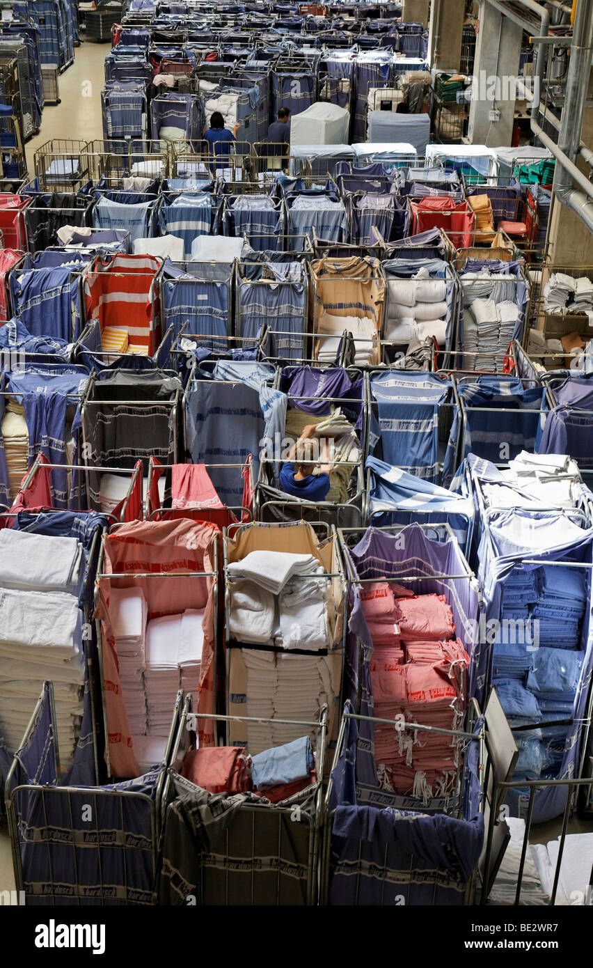 Freshly laundered rental linen sorted in trolleys and waiting in a room to be pressed Stock Photo