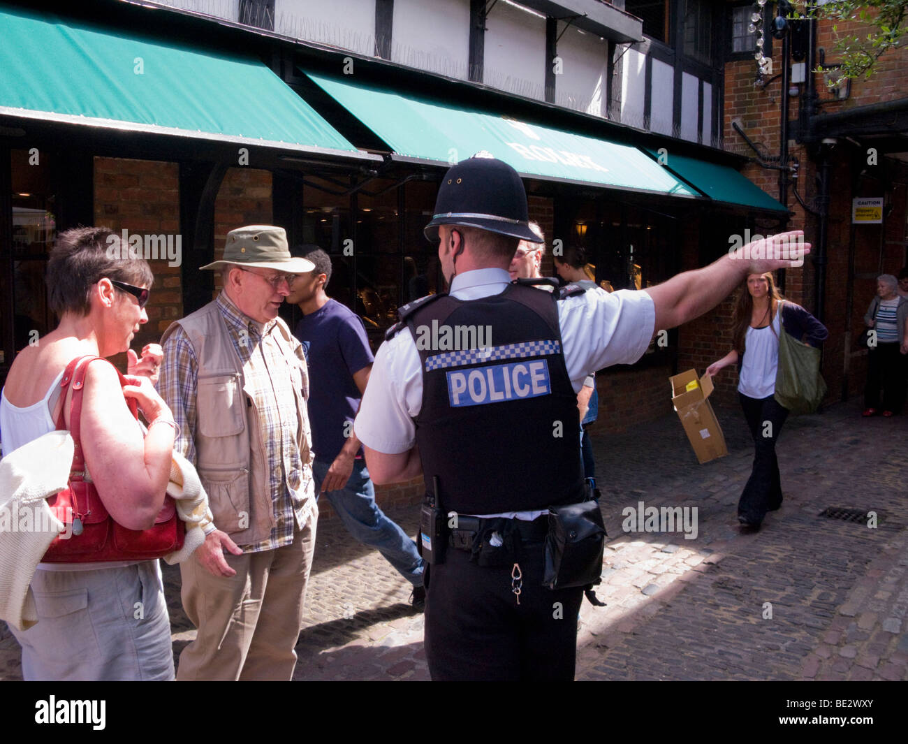 Police Officer gives directions to a tourist in the Lion and Lamb courtyard. Farnham, Surrey. UK Stock Photo