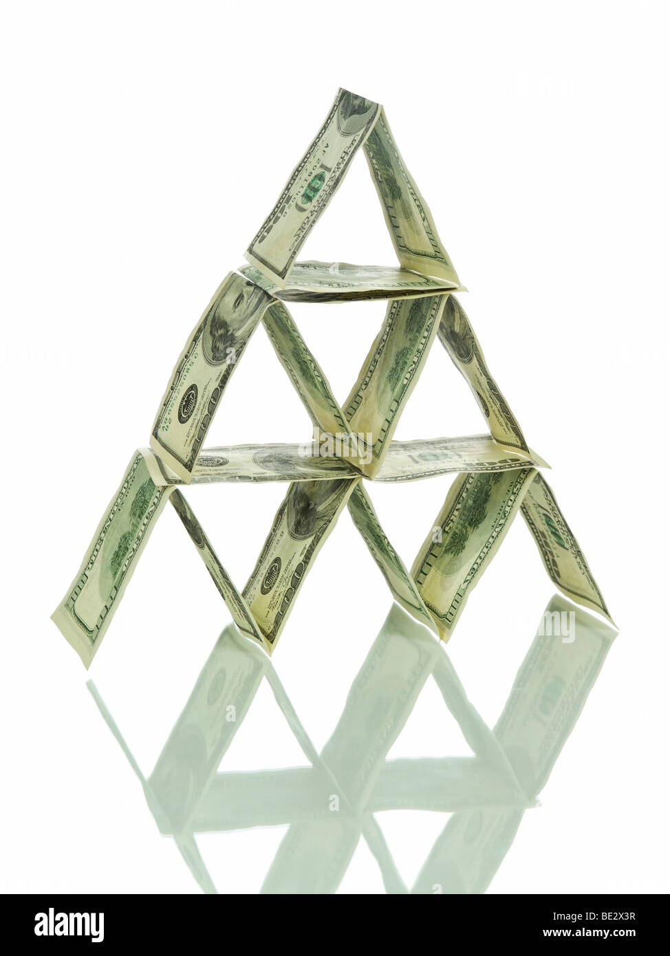 A pyramid made out of one hundred dollar bills and its reflection. Isolated on white. Stock Photo