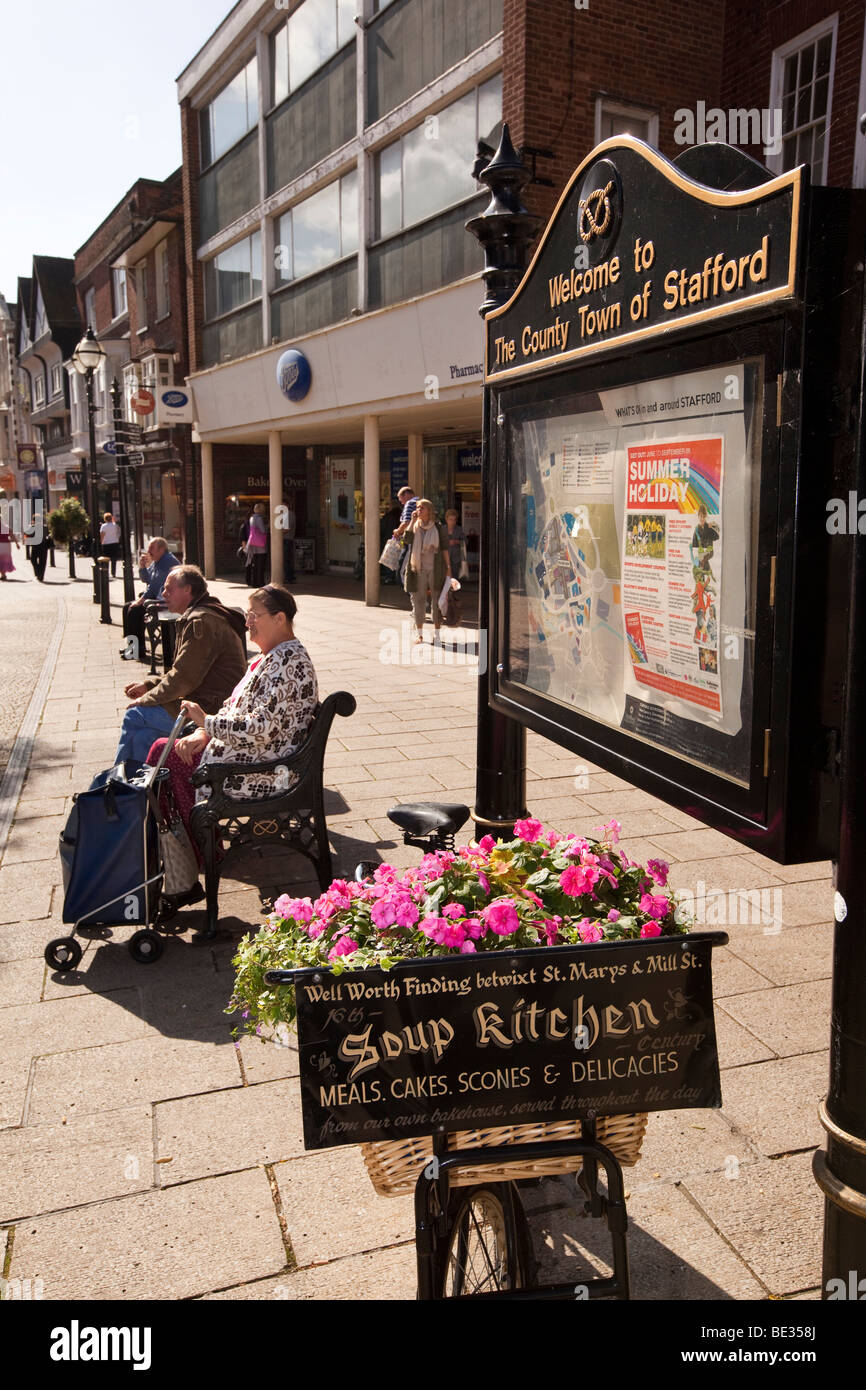 UK, England, Staffordshire, Stafford, Market Square shoppers relaxing on bench in sunshine Stock Photo