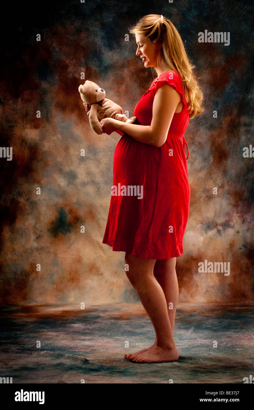 pregnant woman standing holding teddy bear Stock Photo