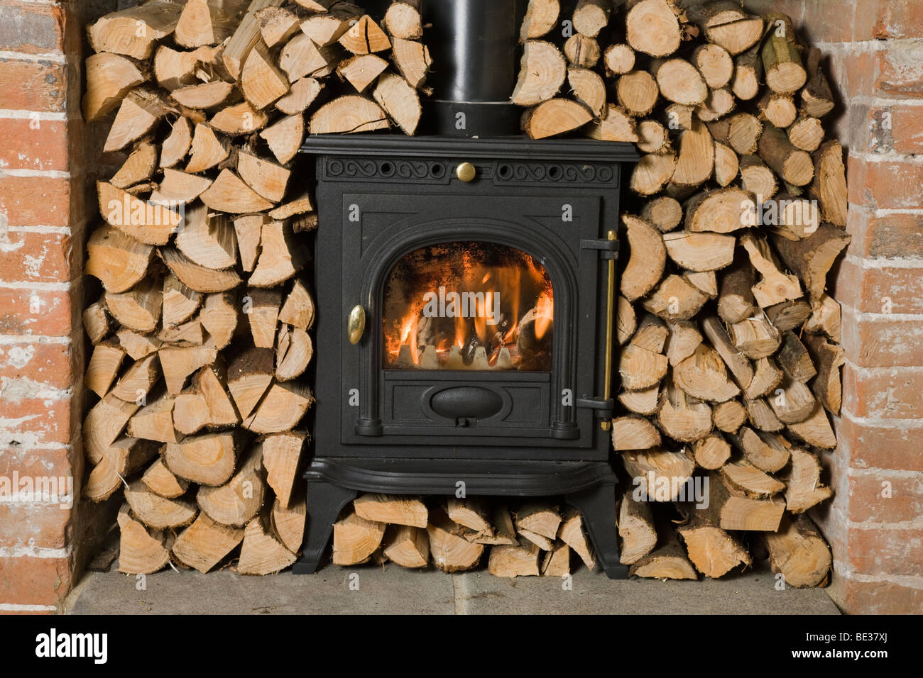 Wood burning stove surrounded by chopped and stacked firewood ready for