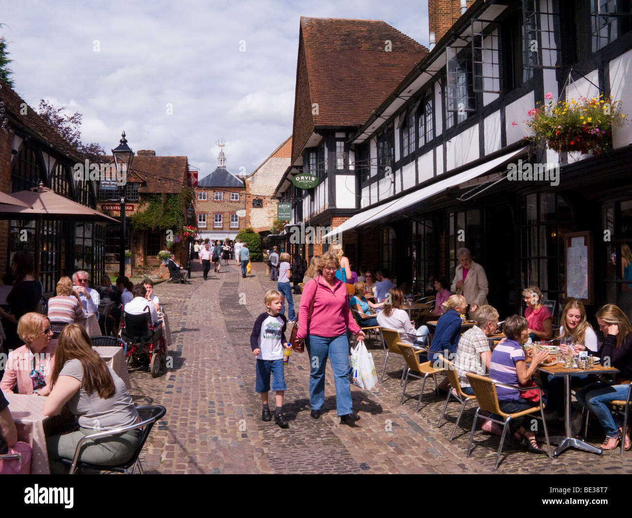 The Lion and Lamb courtyard. Farnham, Surrey. UK. Lion and Lamb cafe is to the right, with people eating at pavement tables. Stock Photo